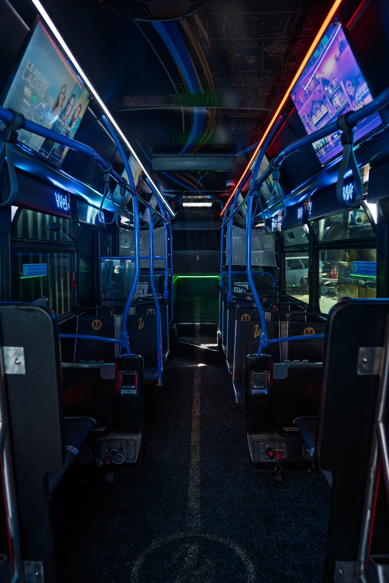 Interior of a West Coast Customs customized bus with screens and colorful LED lighting