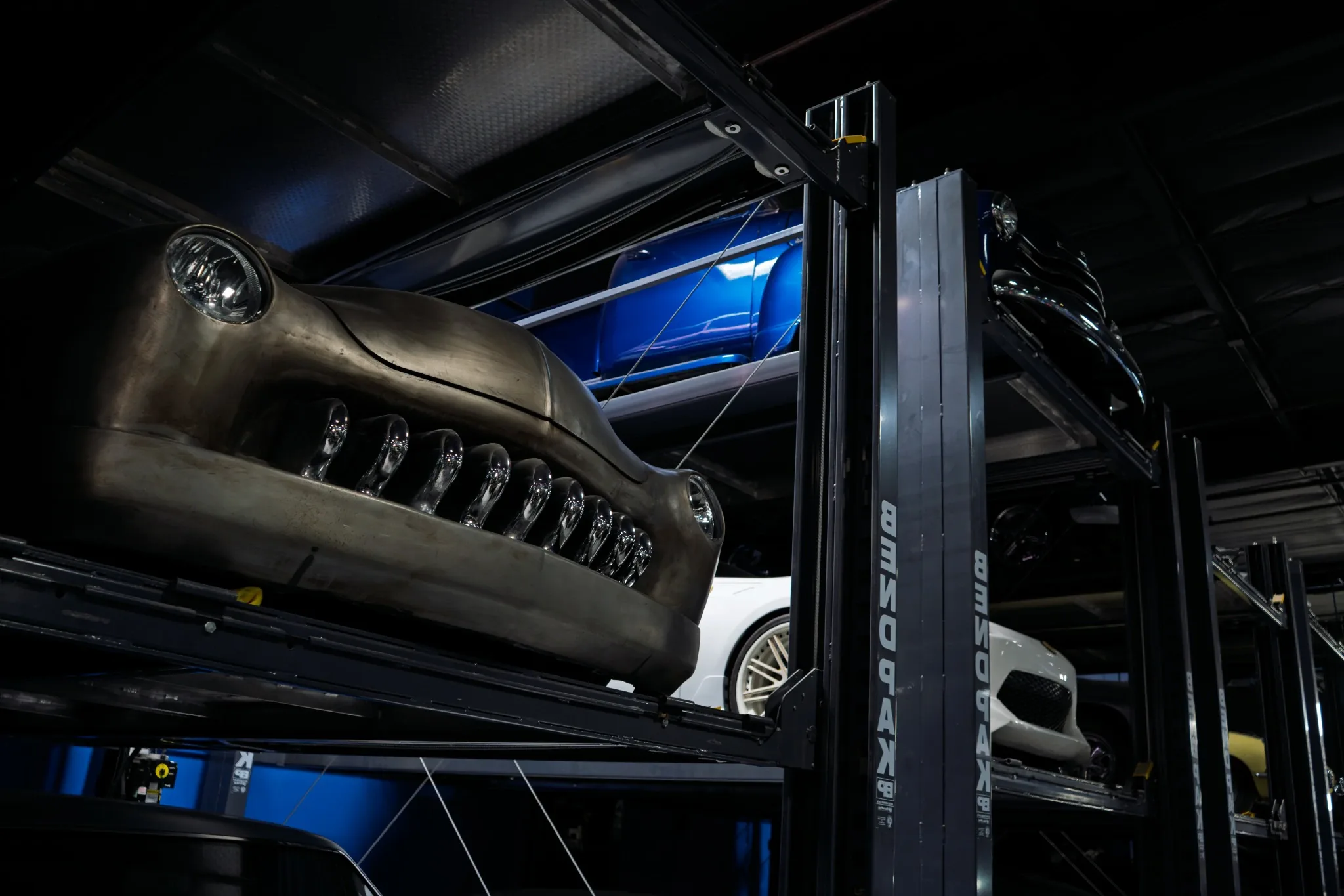 Custom vehicles stored on indoor lifts at West Coast Customs
